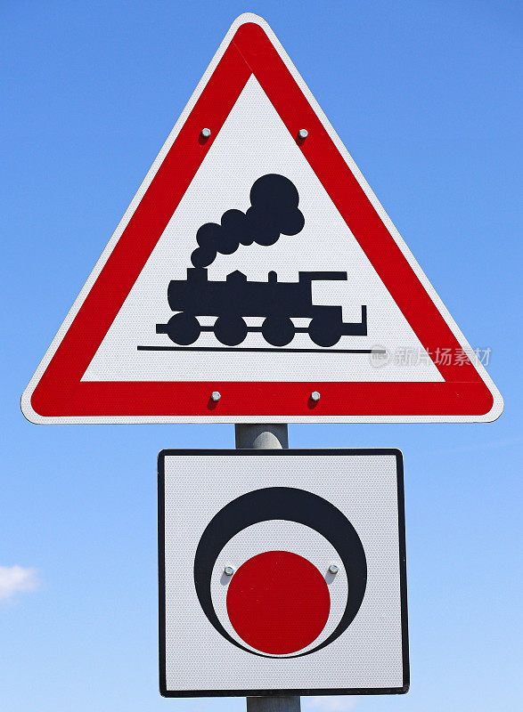 Train crossing road sign against blue sky